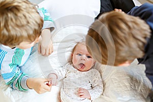 Two little kids boys playing with newborn baby sister girl