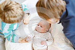 Two little kids boys playing with newborn baby sister girl