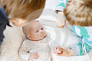 Two little kids boys playing with newborn baby sister girl