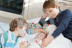 Two little kids boys playing with newborn baby sister girl