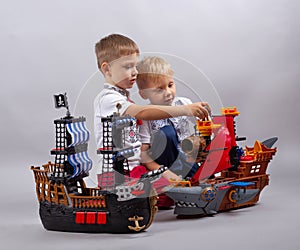 Two little kids boys playing with sailing ship model