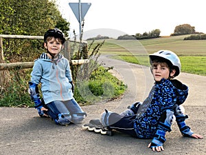 Two little kids boys skating with rollers in the city. Happy children, siblings and best friends in protection safety