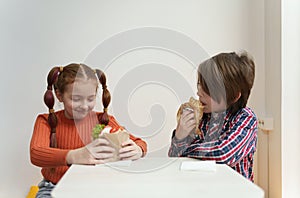 Two little kids eating gyros and souvlaki in Greek restaurant. Elementary age boy and girl enjoying lunch in fast food cafe