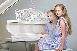 Two little kids girl and boy playing piano in living room or mus