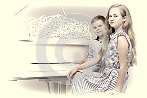 Two little kids girl and boy playing piano in living room or mus