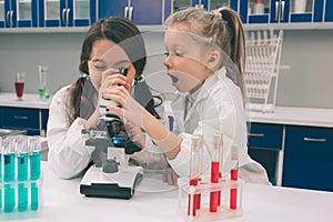 Two little kids in lab coat learning chemistry in school laboratory. Young scientists in protective glasses making