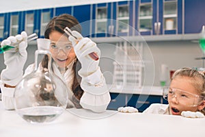 Two little kids in lab coat learning chemistry in school laboratory. Young scientists in protective glasses making