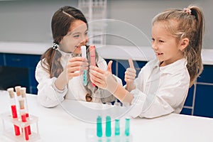 Two little kids in lab coat learning chemistry in school laboratory. Young scientists in protective glasses making