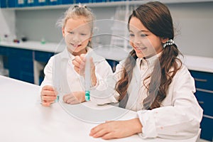 Two little kids in lab coat learning chemistry in school laboratory. Young scientists in protective glasses making