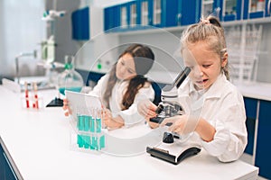 Two little kids in lab coat learning chemistry in school laboratory. Young scientists in protective glasses making