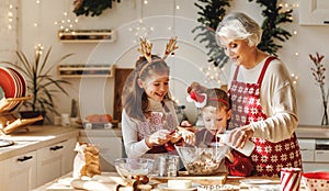 Two little kids making Christmas homemade cookies together with elderly grandmother in kitchen