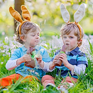 Two little kids playing with Easter chocolate bunny