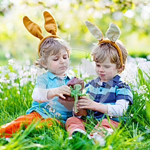 Two little kids playing with Easter chocolate bunny outdoors