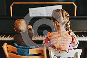 Two little kids playing on piano