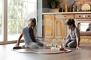 Two little kids playing with toys on warm floor