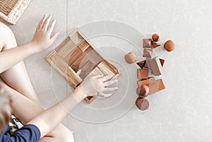 two little kids playing with wood blocks on the floor with a basket