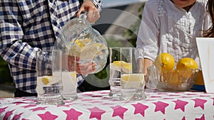 Two little kids are selling lemonade at a homemade lemonade stand on a sunny day with a price sign for an entrepreneur