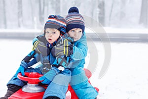 Two little kids sitting together on sledge on cold day