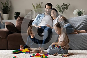 Two little kids together while parent relaxing on comfortable couch