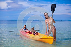 Two little kids and young mom kayaking at tropical