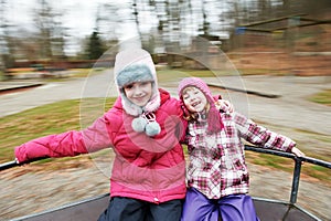 Two little laughing kids girls on carrousel