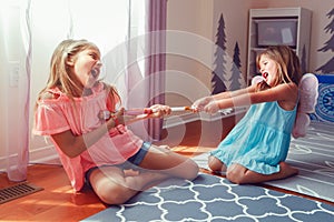 Two little mad angry girls sisters having fight at home. Friends girls can not share a toy. Lifestyle authentic funny family