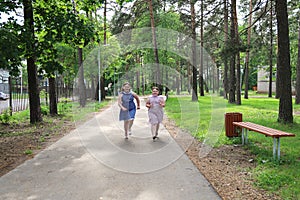 Two little overweight joyful girls run along a path in a deserted park