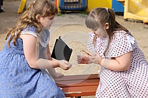 Two little plump girls exchange data from their electronic devices