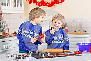 Two little preschool boys baking gingerbread cookies. Happy siblings, children in xmas sweaters. Kitchen decorated for