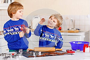 Two little preschool boys baking gingerbread cookies. Happy siblings, children in xmas sweaters. Kitchen decorated for