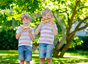 Two little preschool kid boys eating watermelon in summer