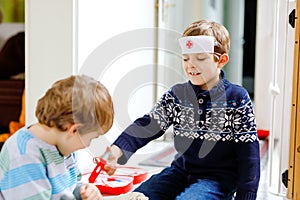 Two little school kid boys playing doctor with toy set. Happy healthy children, siblings and best friends having fun