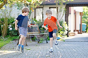 Two little school and preschool kids boys playing hopscotch on playground