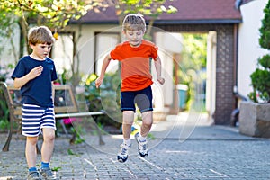 Two little school and preschool kids boys playing hopscotch on playground