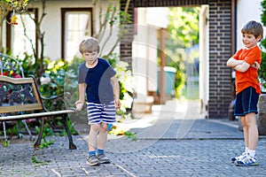 Two little school and preschool kids boys playing hopscotch on playground