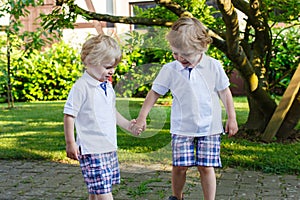 Two little sibling boys having fun outdoors in family look