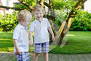 Two little sibling boys having fun outdoors in family look