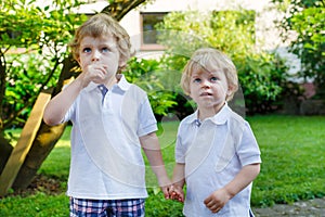Two little sibling boys having fun outdoors in family look