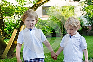 Two little sibling boys having fun outdoors in family look