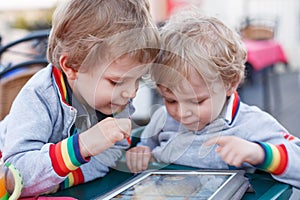 Two little sibling boys having fun together with tablet pc.