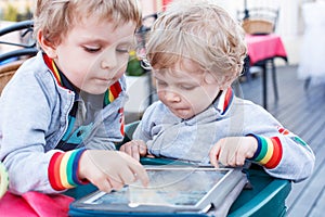 Two little sibling boys having fun together with tablet pc.