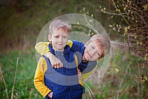 Two little sibling boys hugging and having fun outdoors n the wa