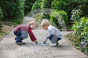 Two little sibling boys painting with chalk outdoors