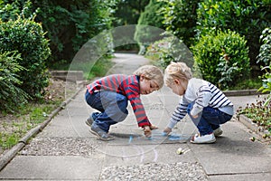 Two little sibling boys painting with chalk outdoors