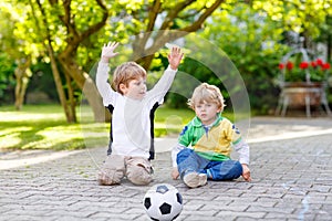 Two little sibling boys playing soccer and football