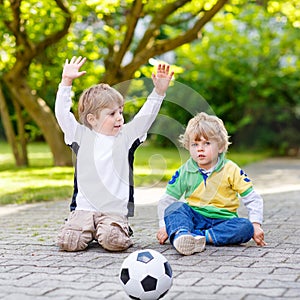 Two little sibling boys playing soccer and football