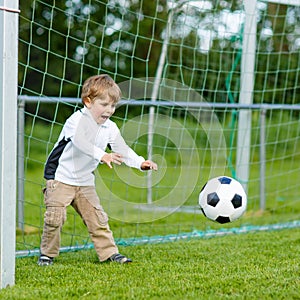 Two little sibling boys playing soccer and football on field