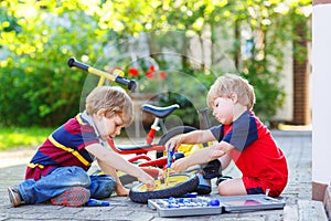 Two little sibling boys repairing broken bike