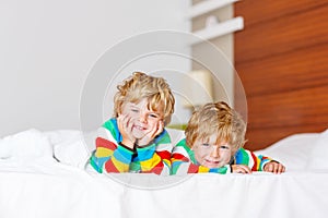 Two little sibling kid boys having fun in bed after sleeping