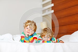 Two little sibling kid boys having fun in bed after sleeping